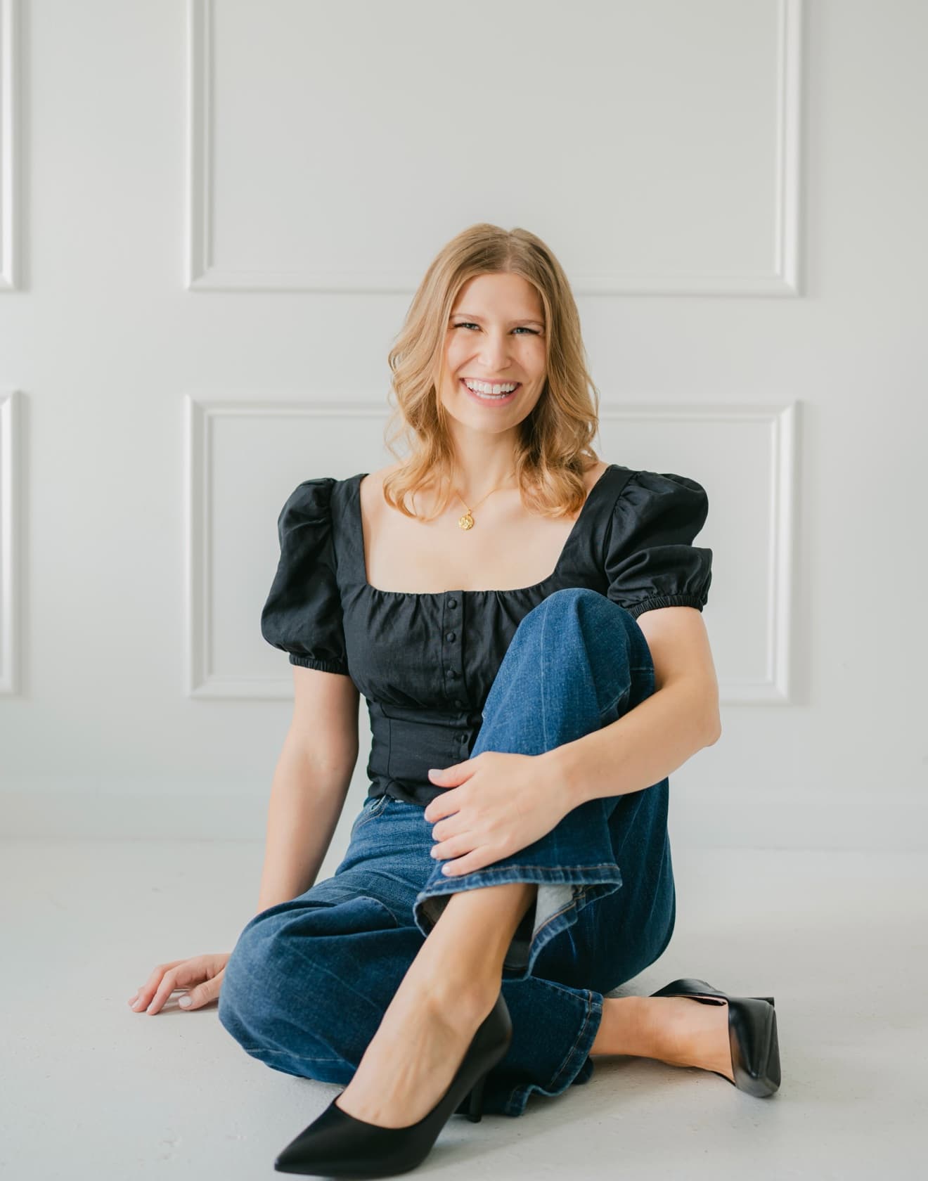 Christine Cornellier, seated on the floor against a paneled white wall
